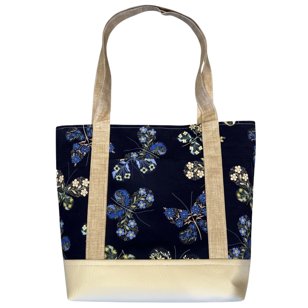 Handmade cotton tote bag featuring blue botanical florals on a navy background with natural linen handles and ivory faux leather base