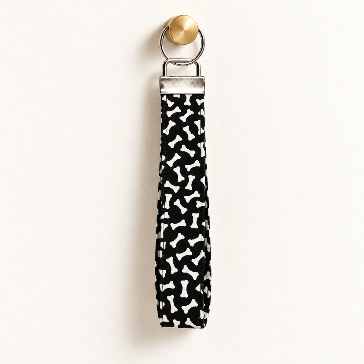 Bone to Pick – Fabric Wristlet Keychain hanging from a gold wall knob