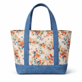 Cotton tote bag with beige floral print and blue straps and base, featuring a structured shape and front exterior pocket