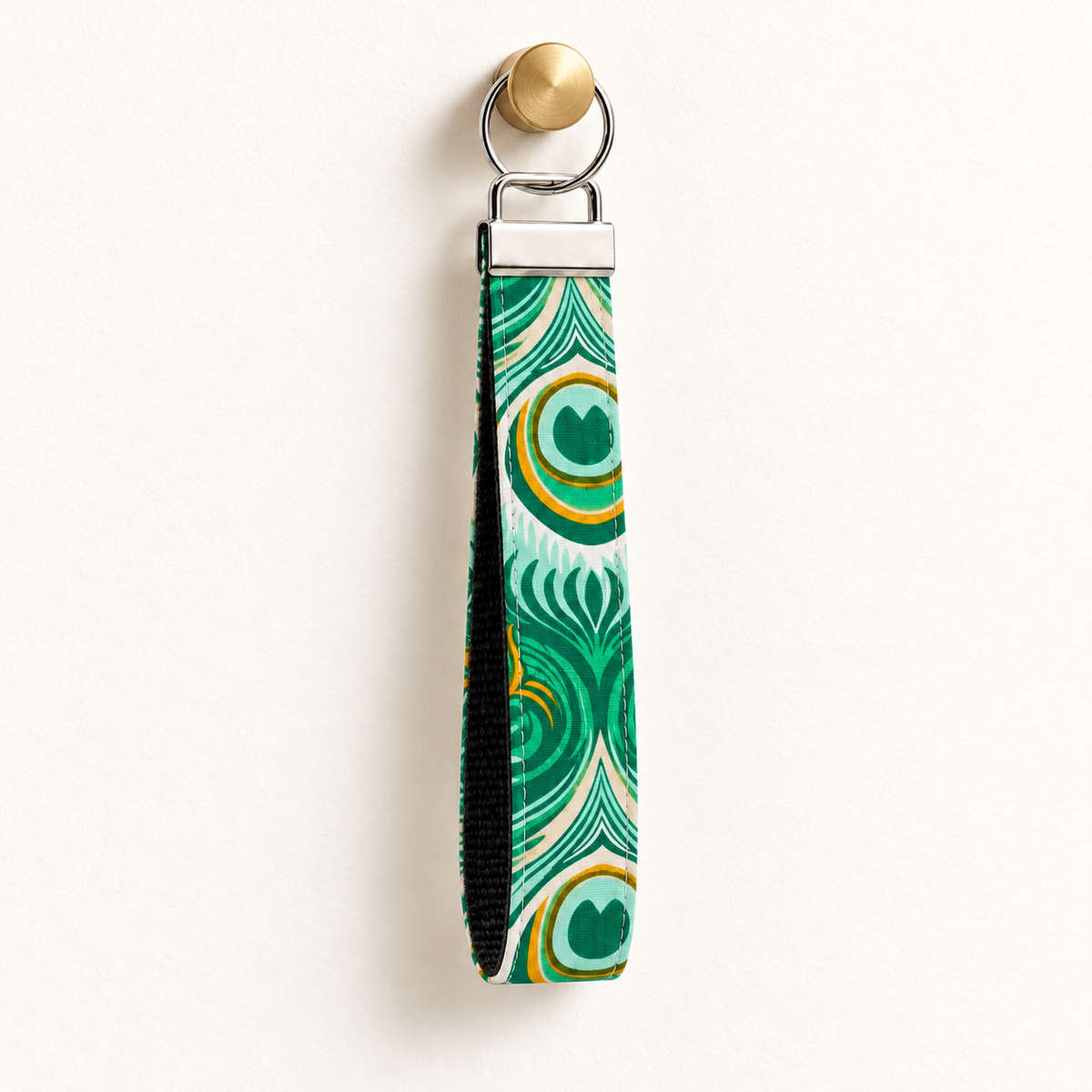 Full Plume – Fabric Wristlet Keychain hanging from a gold wall knob