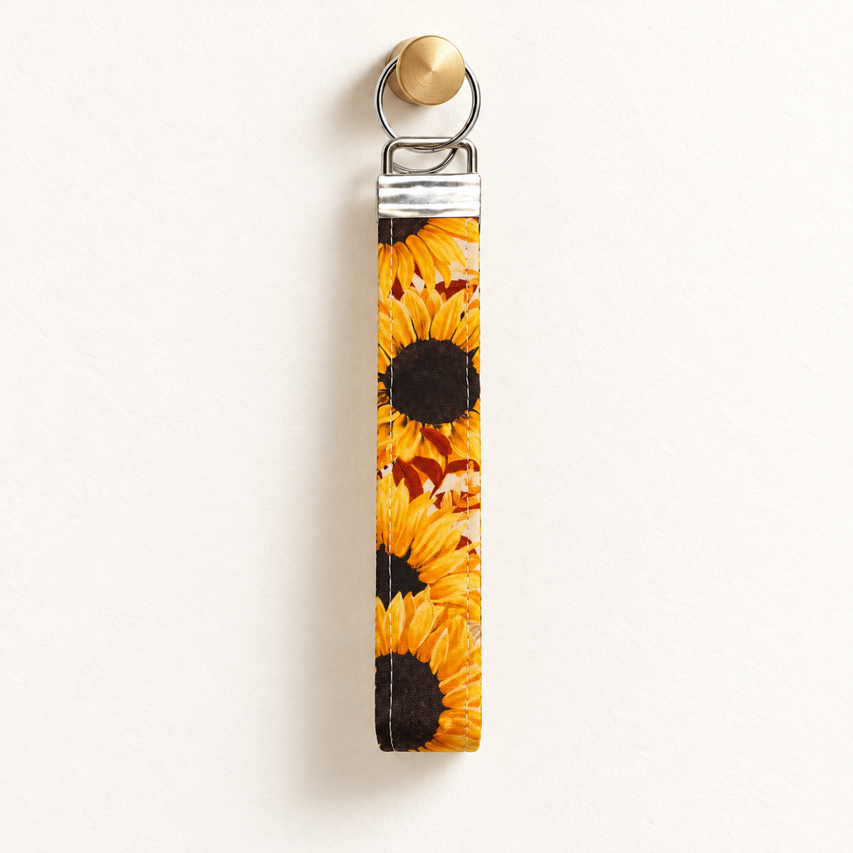 Here Comes the Sun – Fabric Wristlet Keychain hanging from a gold wall knob