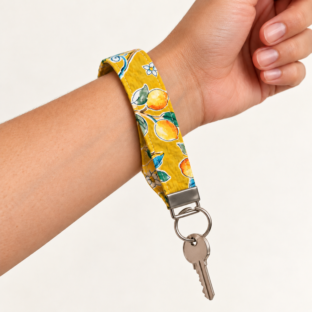 Lemon Main Character – Fabric Wristlet Keychain worn around a wrist with a key attached