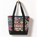 Handmade cotton tote bag with retro pixel floral pattern and black cross detail straps hanging on a gold knob