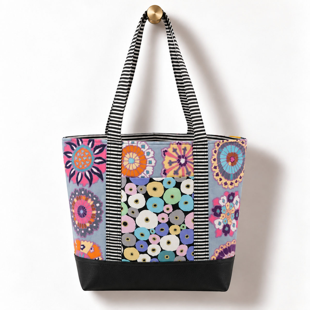 Handmade cotton tote bag with colorful boho medallion pattern and striped straps hanging on a gold knob
