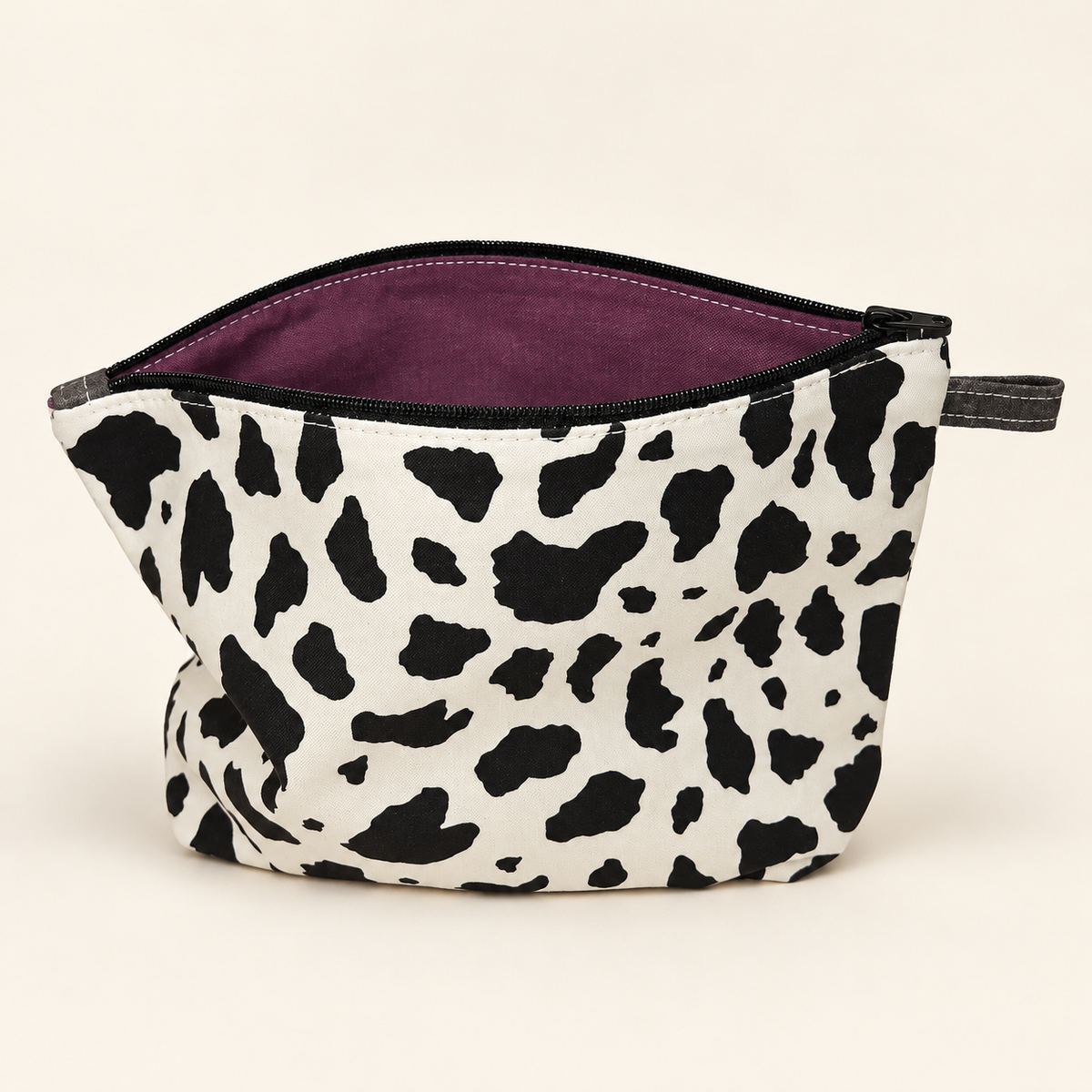 Moo-d Swing cow print cotton pouch standing with plum lining visible.