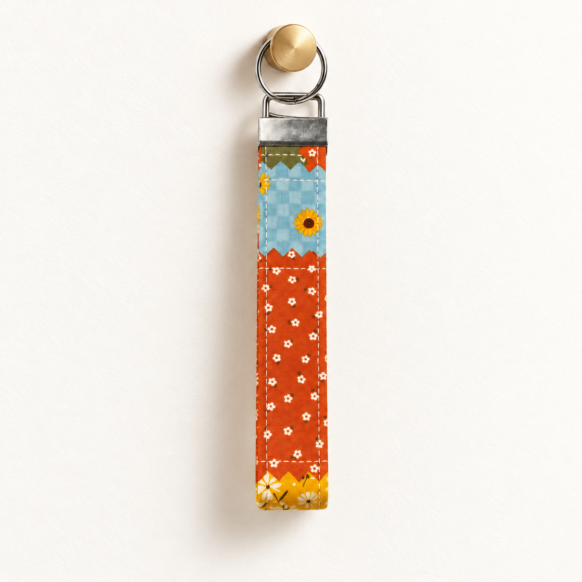 Patch Me Outside – Fabric Wristlet Keychain hanging from a gold wall knob
