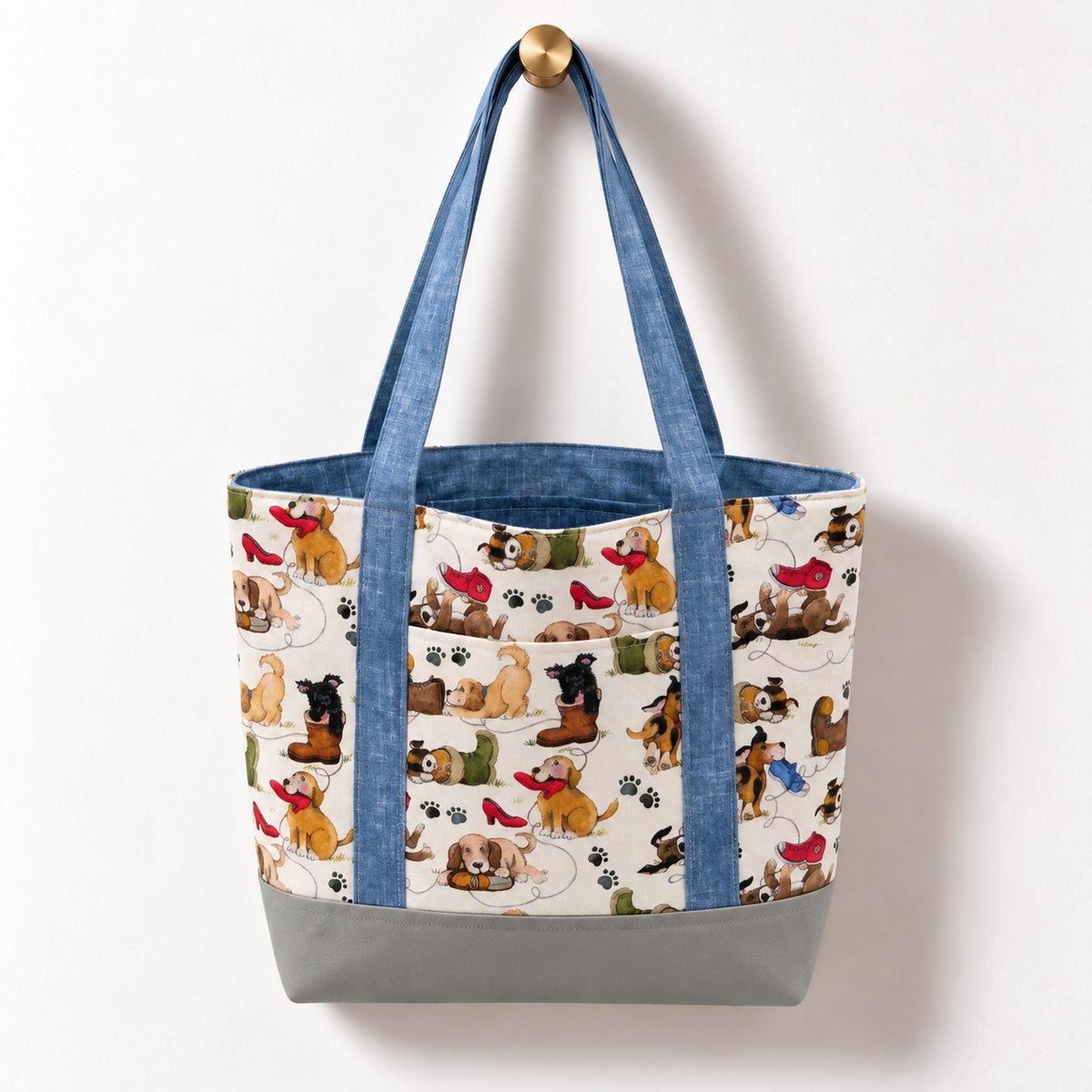 Playful Puppies Cotton Tote Bag – Gray & Blue hanging on a gold knob