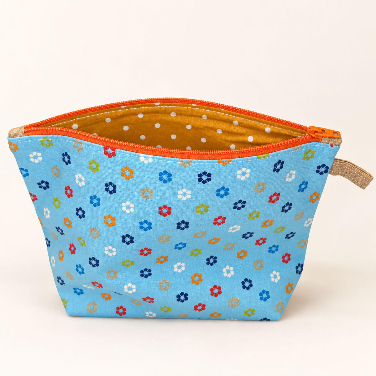 Petal Pop sky blue floral cotton pouch with orange zipper, standing view showing mustard polka-dot lining