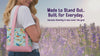 woman holding bird bag with pink dot accent in front of a lavender field.