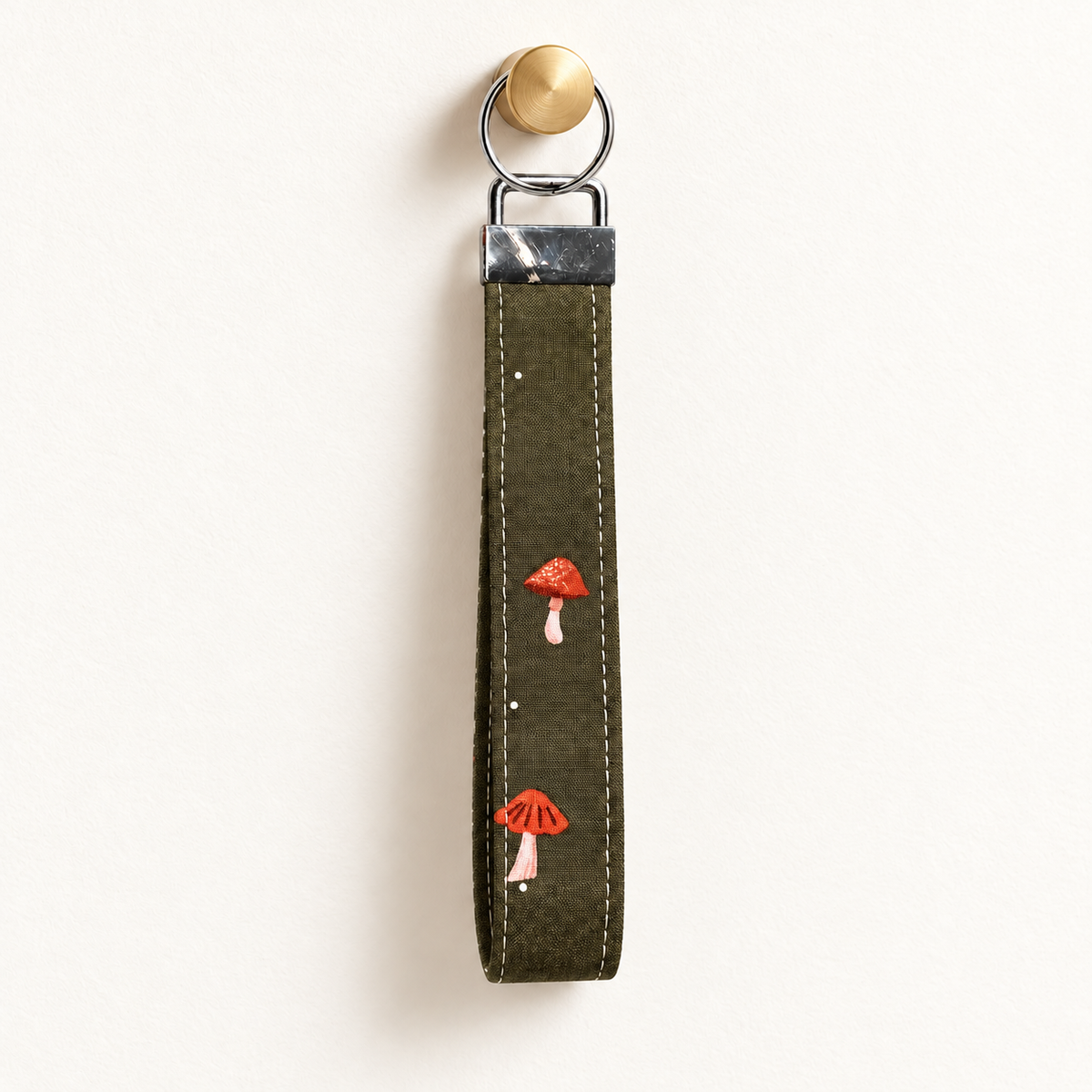 Shroom Service – Fabric Wristlet Keychain hanging from a gold wall knob