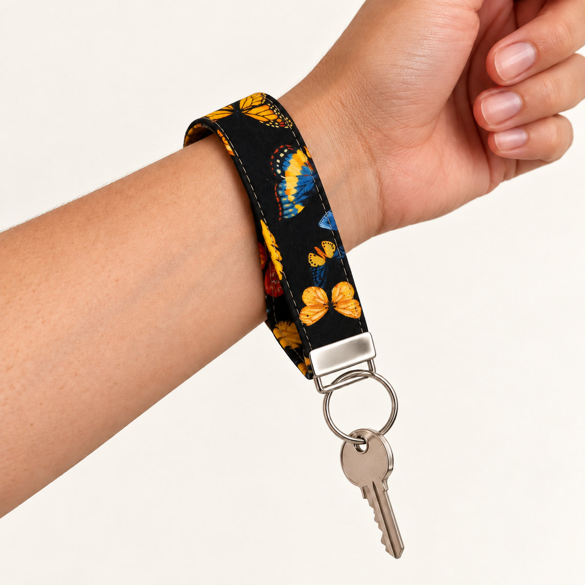 Social Butterfly – Fabric Wristlet Keychain worn around a wrist with a key attached
