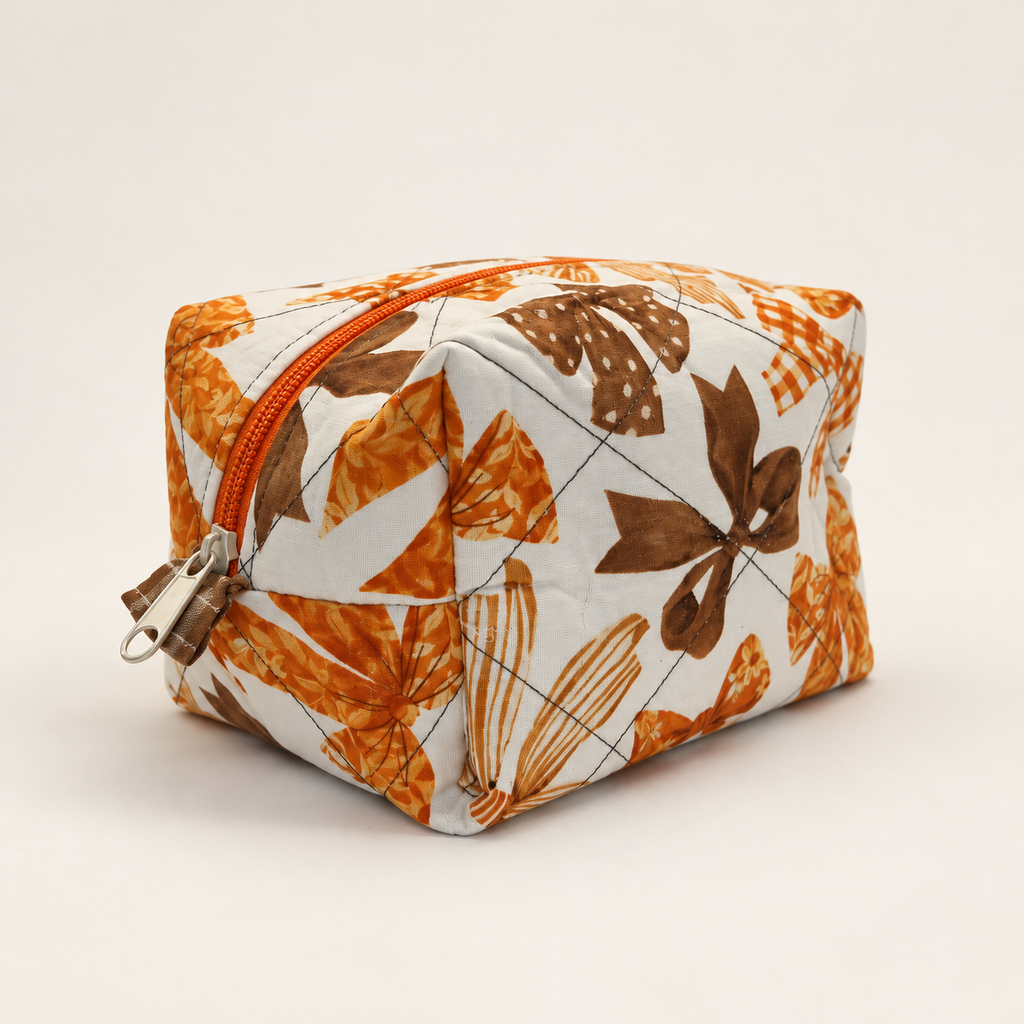 Three-quarter view of Take a Bow quilted cotton Mini Moment boxy bag showing orange zipper
