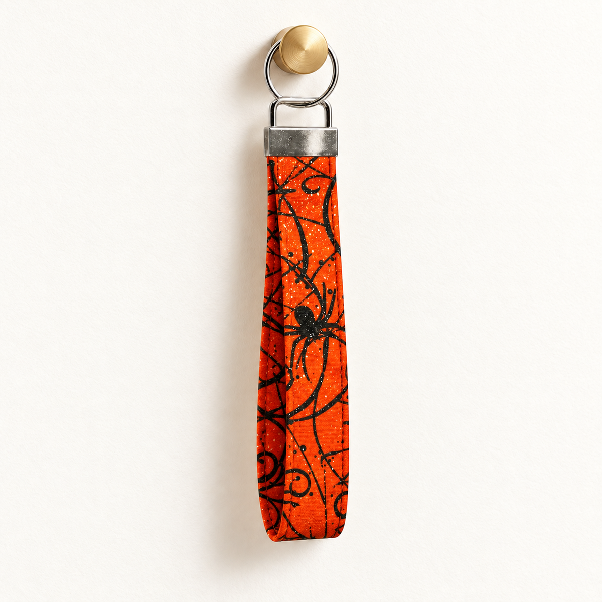 Web Hot – Fabric Wristlet Keychain hanging from a gold wall knob