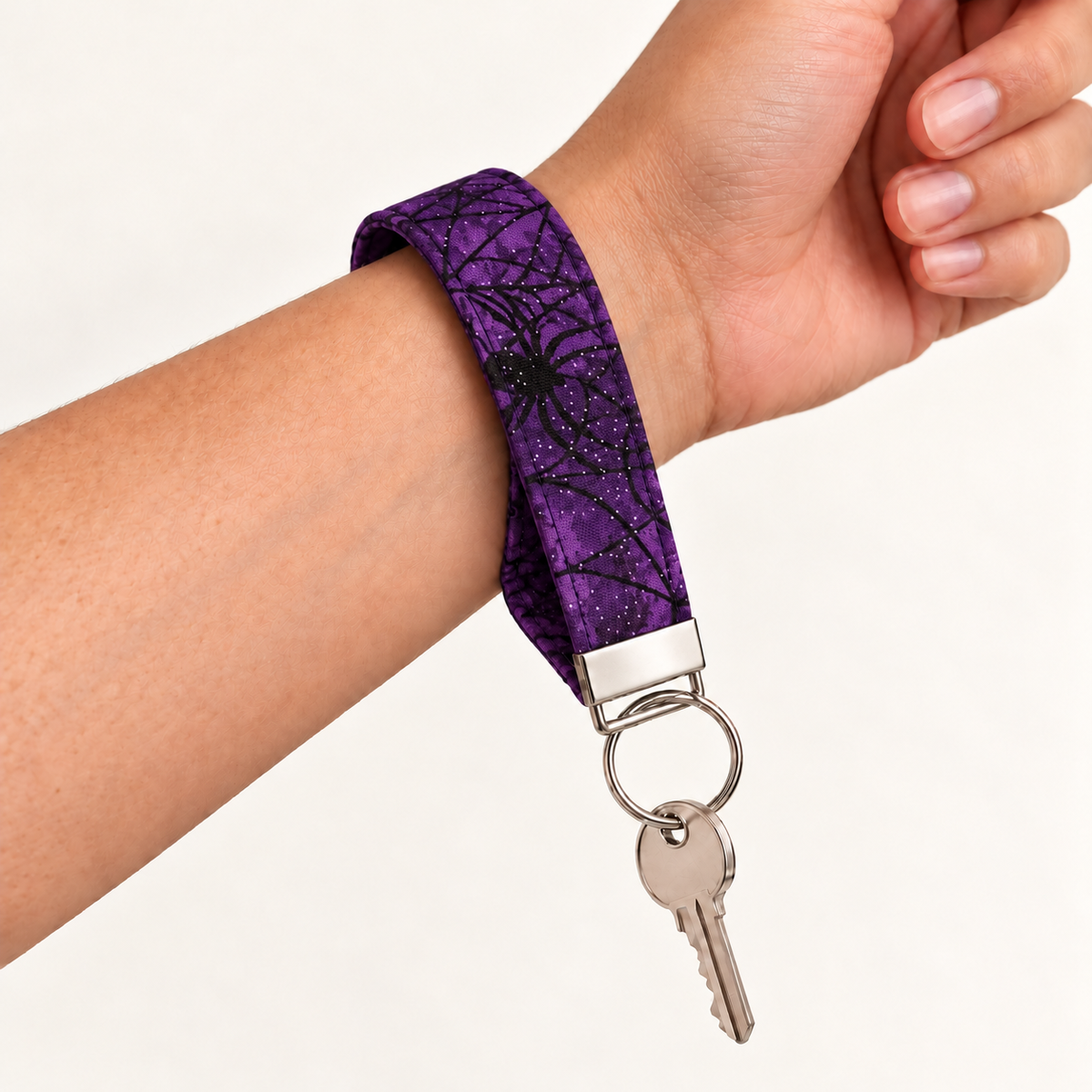 Web of Sass – Fabric Wristlet Keychain worn around a wrist with a key attached